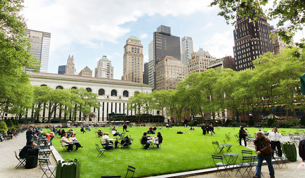 A group of people walking in a park with Bryant Park in the background