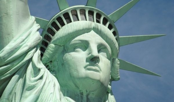 A close up of a statue of a person with Statue of Liberty in the background