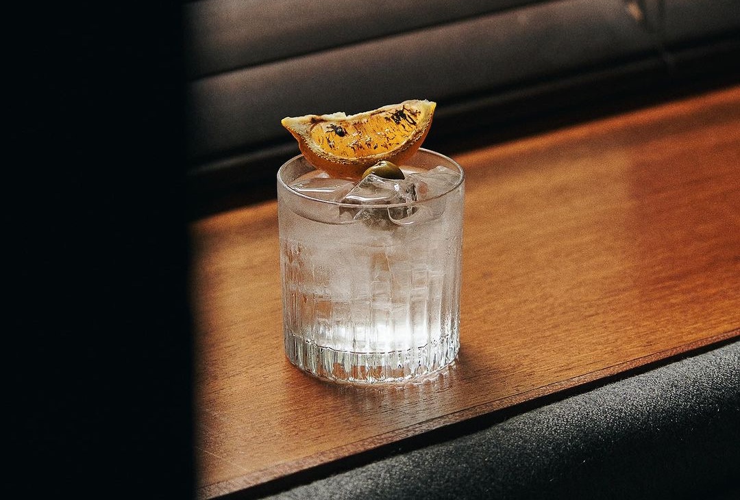 Clear cocktail with charred orange garnish