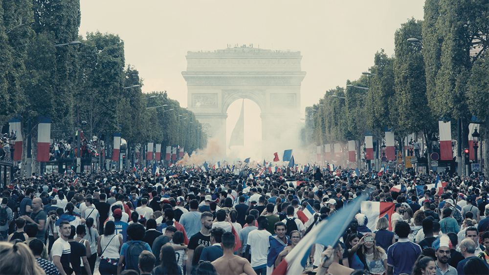 A group of people standing in front of a large crowd of people with Champs-Élysées in the background