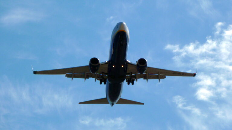 A large passenger jet flying through a cloudy blue sky