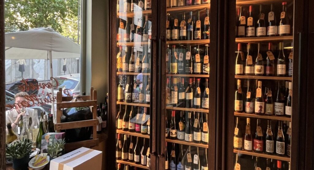 A bottle of wine next to a book shelf filled with books