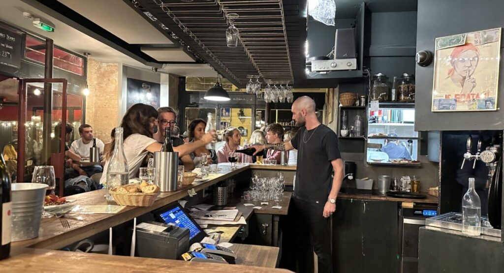 Bartender pouring wine behind bar of Le Barav