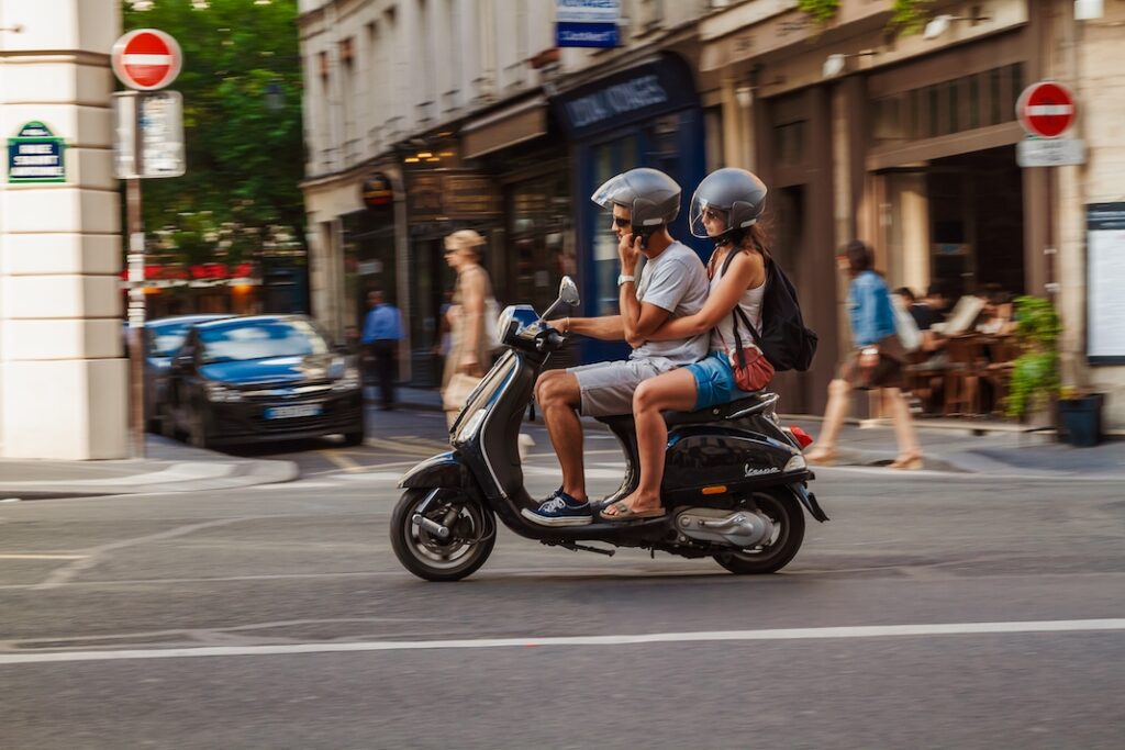 PARIS, FRANCE - AUGUST 09, 2012: A Young Couple Rides Vespa Scooter Through Paris Street.