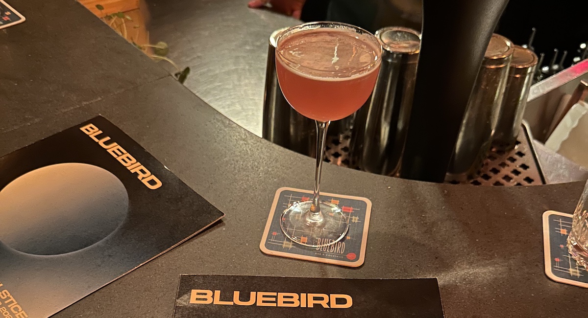 Cocktail in coupe glass on bar with menus