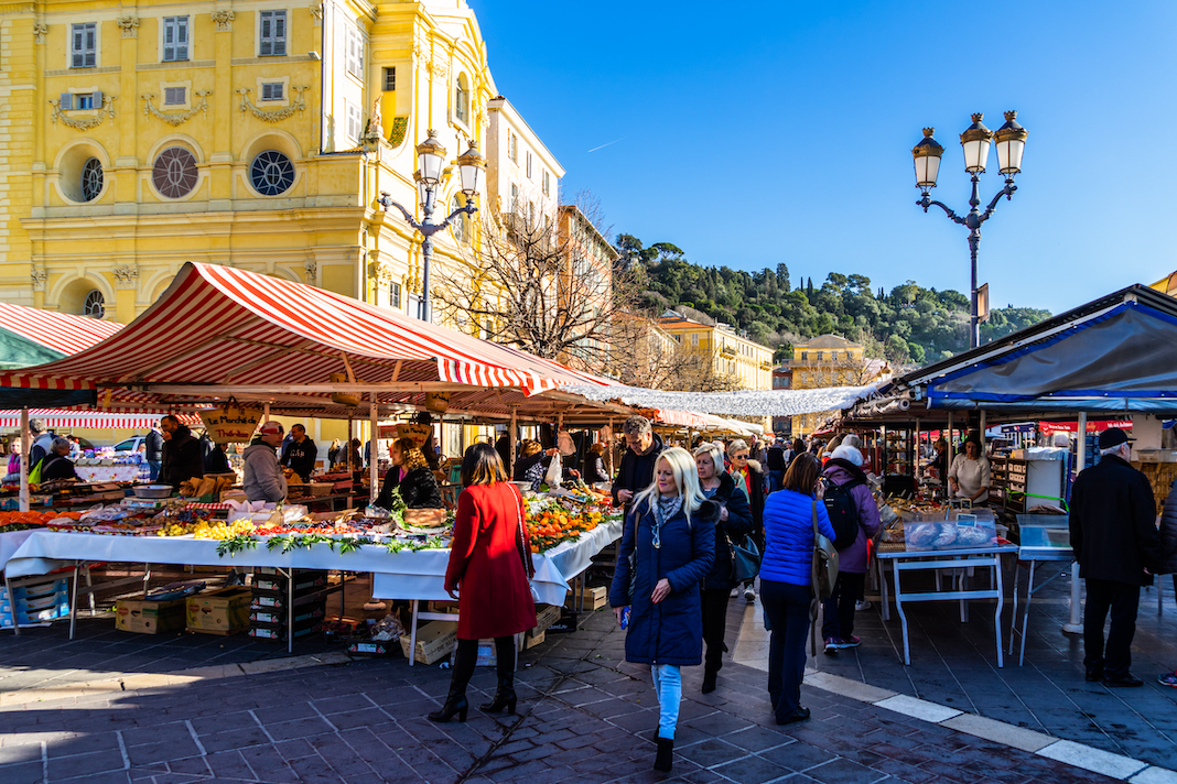 Nice, France, January 2020 - Tourists and locals strolling between the market stalls at the Cours Saleya in Nice.