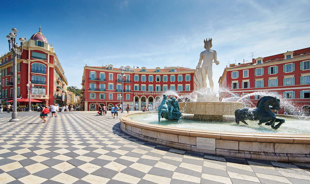 France, Nice, 08.09.2015: Fountain of the Sun, Place Massena in center of Nice, Plassa Carlou Aubert, tourism, sunny day, blue sky, square tiles laid out in a checkerboard pattern, Apollo statue