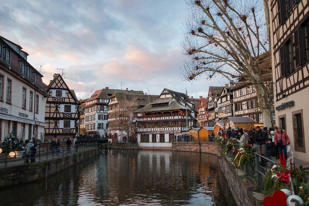 Strasbourg, France – December 9, 2017: Half-timbered house in the district of La Petite France in Strasbourg with incidental people before Christmas