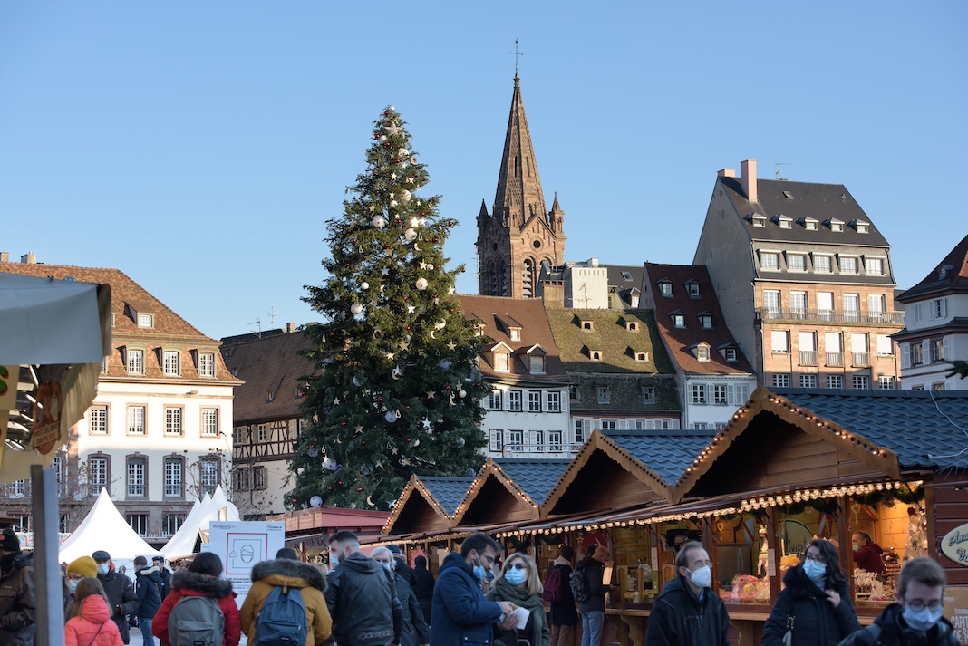 Strasbourg, France - Dec 17, 2021: Central Place Kleber with tall fir Christmas tree annual Christmas Market - market stalls chalets people shopping gifts toys