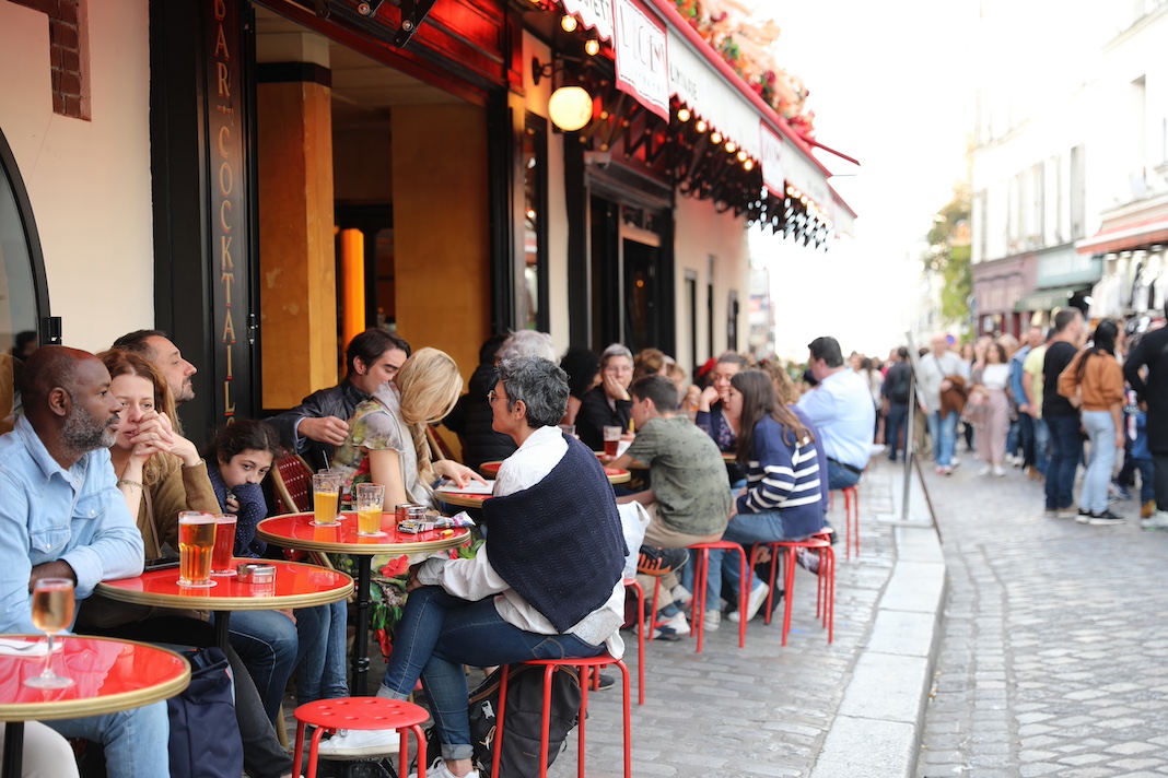 Paris, France, October 29, 2022: A lively crowd of tourists enjoys a warm summer day at a quintessential Montmartre bar in Paris, France, France