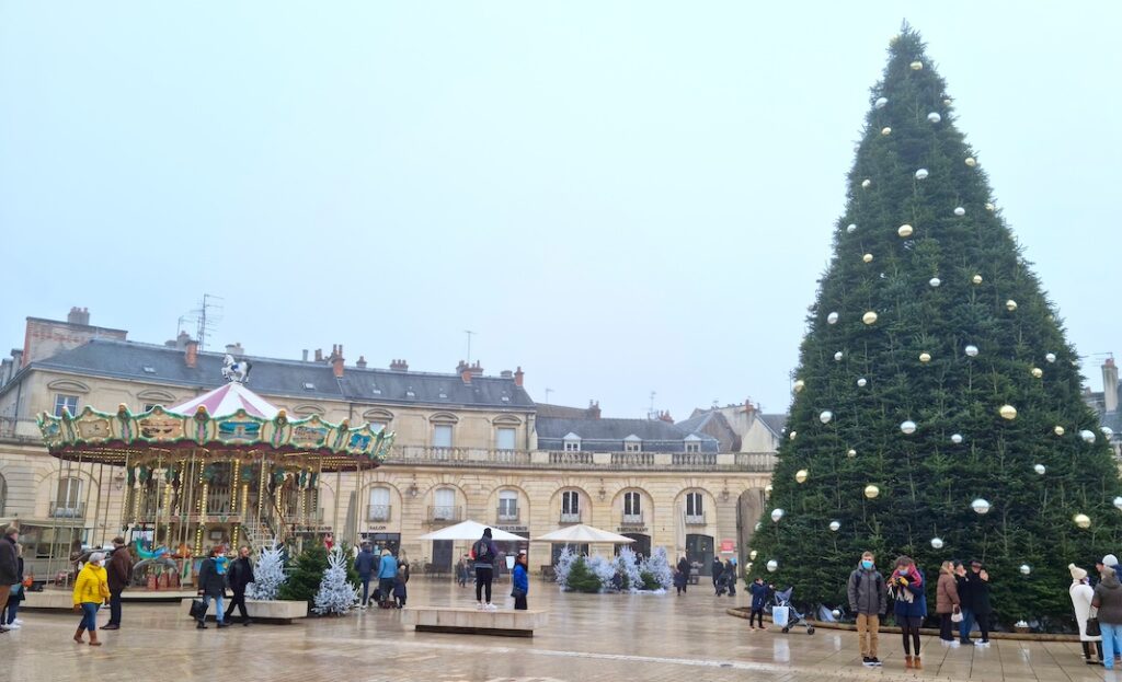 Dijon, France - 31 December, 2022: People walking in the Liberation square (Place de la Liberation) decorated for Christmas. The pedestrian square is located in the center of the history old town.