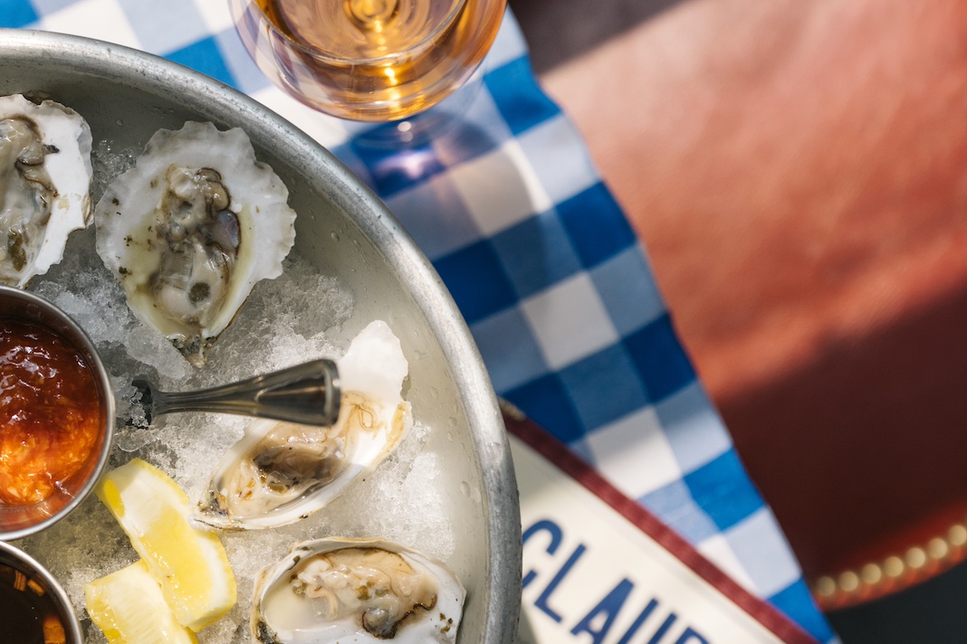 Tray of oysters and rosé wine on blue and white checkered tablecloth
