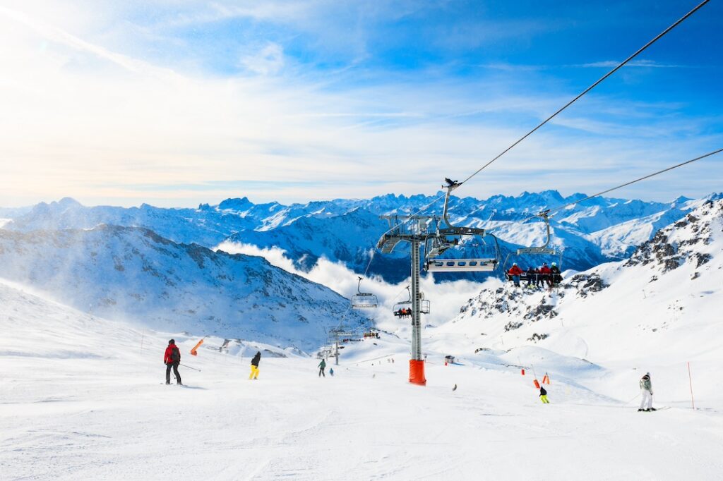 Ski resort in winter Alps. Skiers ride down the slope. Val Thorens, 3 Valleys, France. Beautiful mountains and the blue sky, winter landscape.