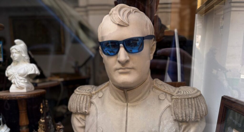 Bust of Napoleon wearing sunglasses in shop window.