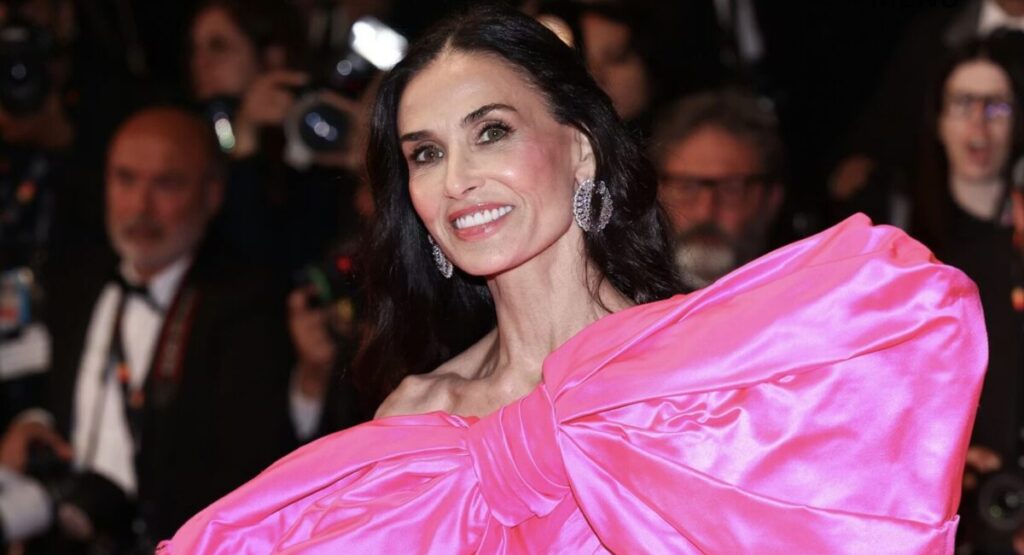 A woman in a hot pink gown surrounded by photographers