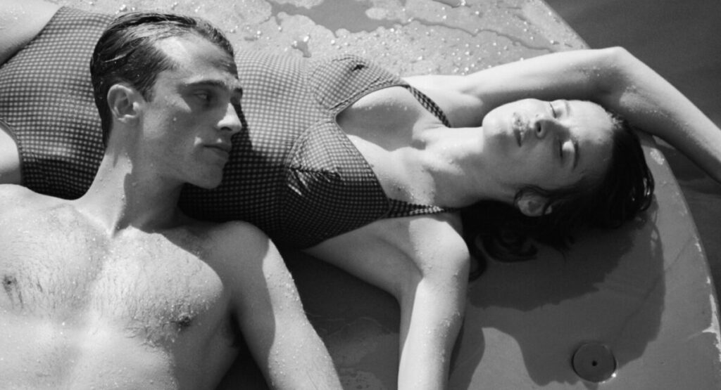 A man rests his head on the stomach of a sleeping woman.