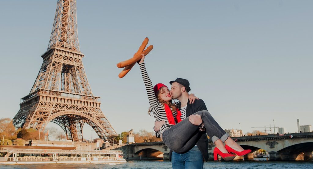Happy French stereotypical couple having fun on a romantic date under the Eiffel Tower in Paris, France.