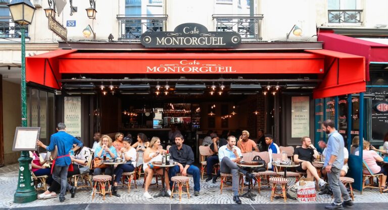 PARIS - AUGUST 23, 2017: People passes by a cafe on Rue Montorgueil street. People have brunch/lunch at cafe and enjoy nice weather on August 23, 2017.