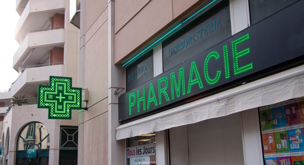 French pharmacy drug store with neon green signage - Pharmacie - on front of a building. Nice, France - September 27, 2021.
