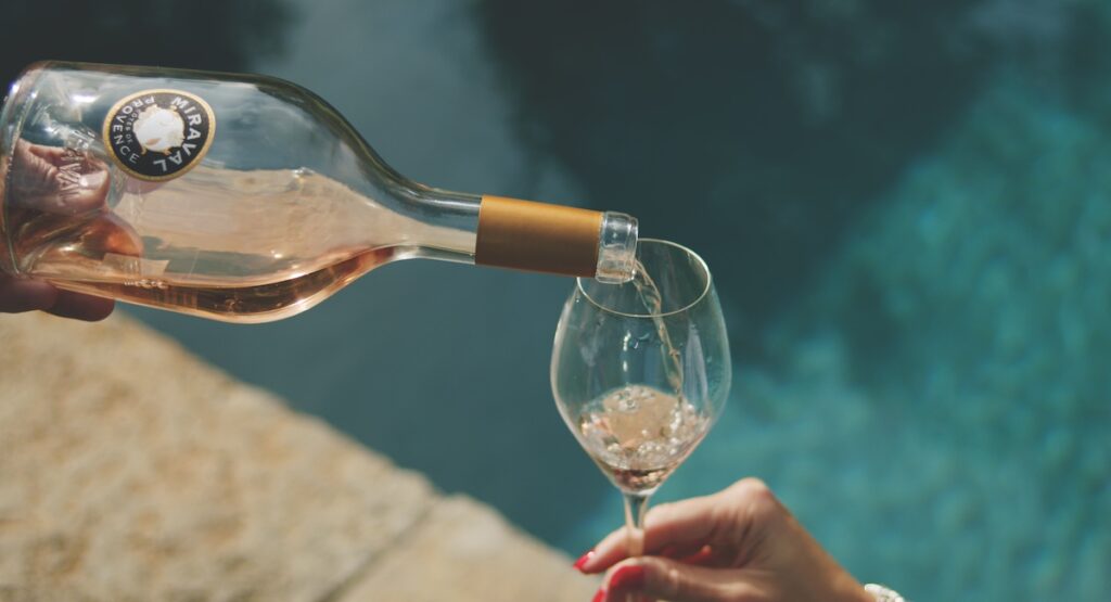 Bottle of rosé wine being poured by pool