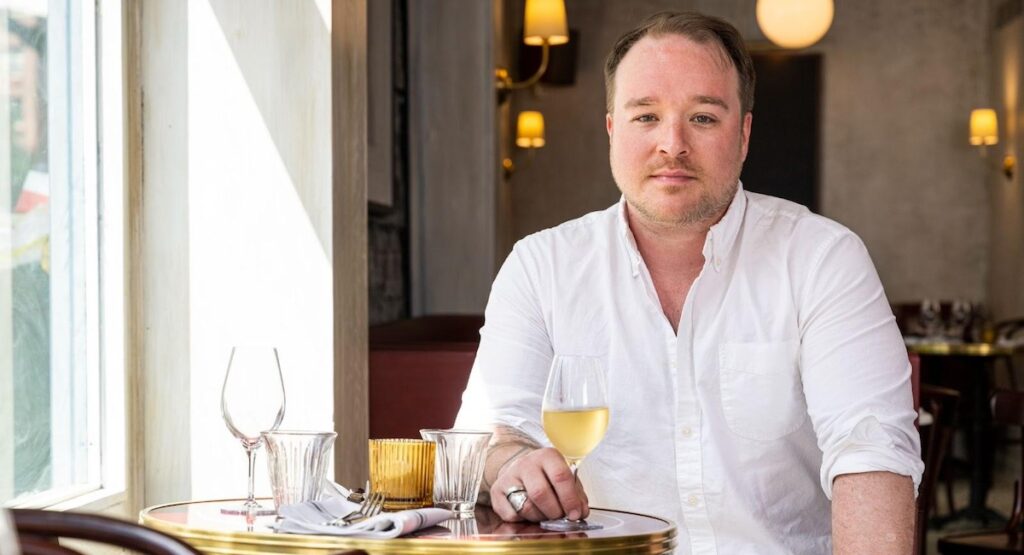 Man drinking white wine at bistro table