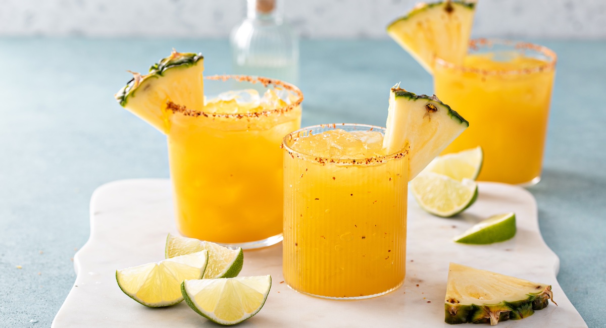 Pineapple cocktail in glasses with chili tajin rim and a slice of pineapple