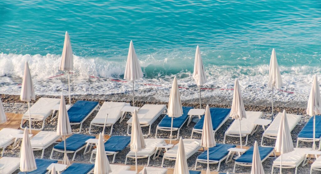 Beach umbrellas and blue loungers Nice, France. French Riviera.