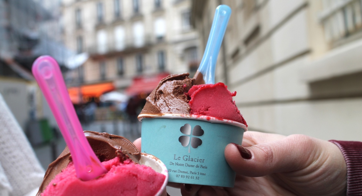 Gelato in multiple flavors in blue paper cup with spoon