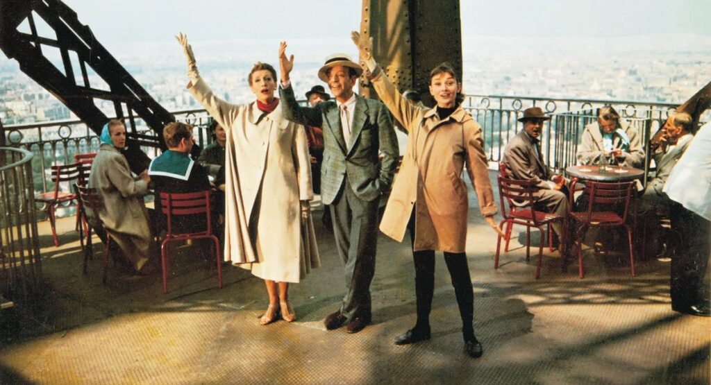 Fred Astaire and Audrey Hepburn waving from the Eiffel Tower platform.
