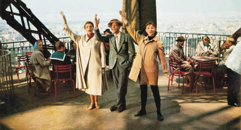 Fred Astaire and Audrey Hepburn waving from the Eiffel Tower platform.