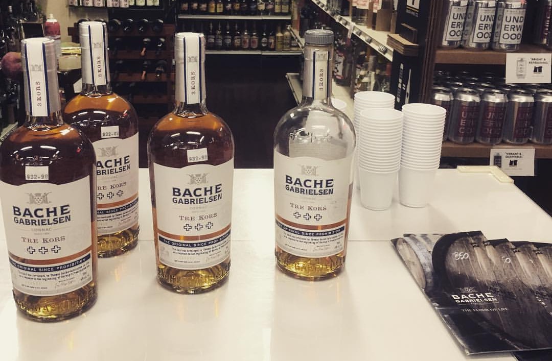 Bottles of cognac in liquor store with tasting cups