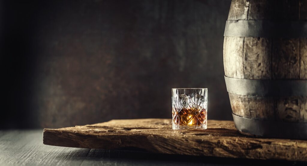Glass of cognac beside barrel