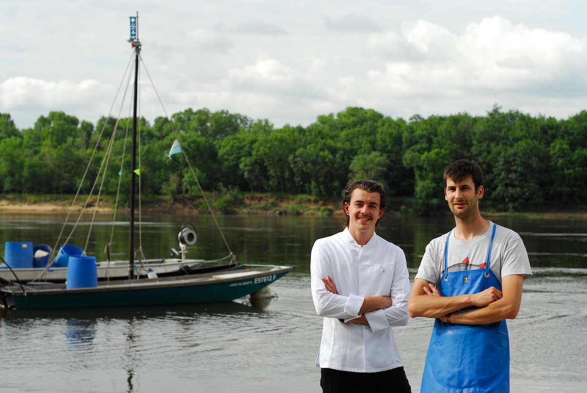 Two men posing in front of river boat
