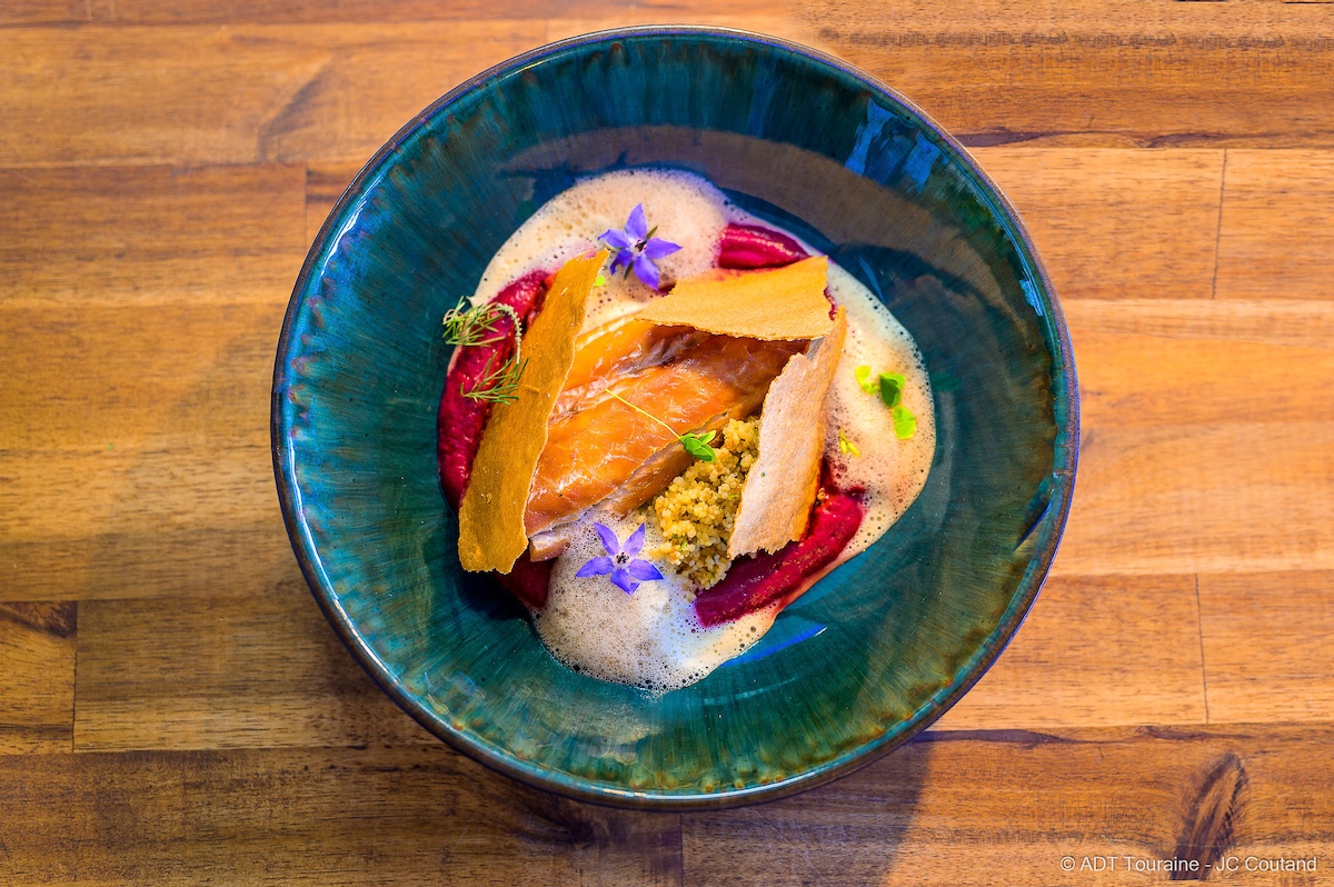 Beautifully plated fish dish in green-blue bowl