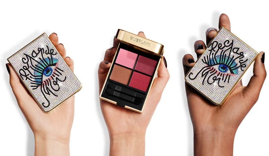 Three hands holding eye shadow palettes