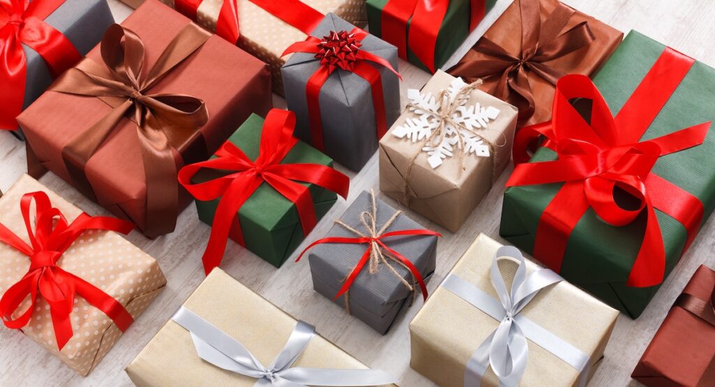 Lots of Gift boxes on white background. Presents in craft and colored paper decorated with red satin ribbon bows.