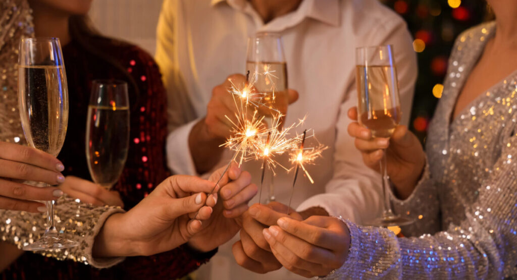 People with champagne and Christmas sparklers at party.