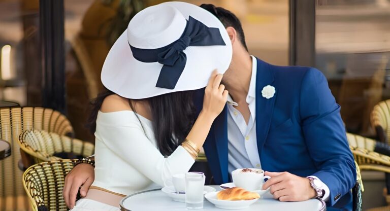 Man and woman with large hat kissing at cafe