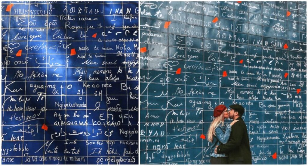A couple is kissing in front of Le mur des je t'aime.