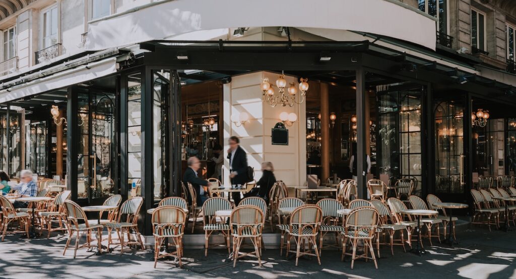 Typical view of the Parisian street with tables of brasserie (cafe) in Paris, France. Architecture and landmarks of Paris. Postcard of Paris