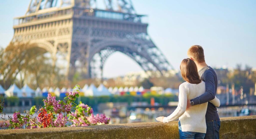 Couple looking at Eiffel Tower on a bridge strewn with flowers
