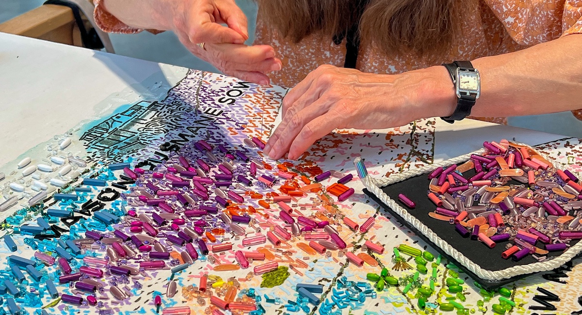 Woman working on craft with colorful pieces.