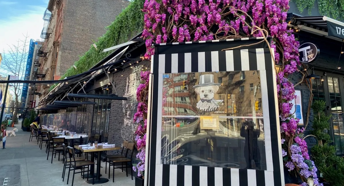Restaurant facade with fake flowers and outdoor seating.