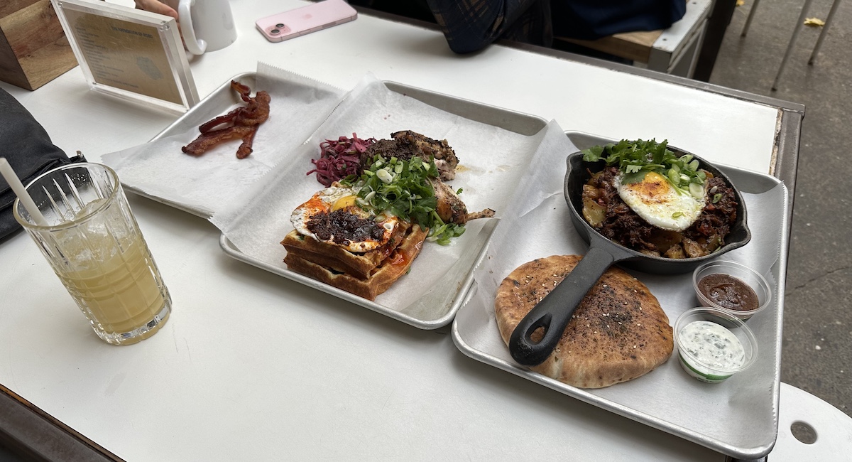 Platters of chicken and waffles and lamb in skillet.