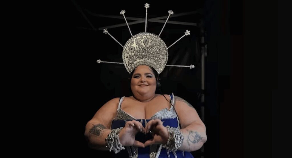 Woman making a heart with her hands, wearing elaborate headdress