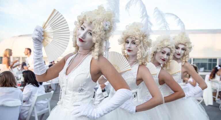 Women in wigs with fans dressed in all white