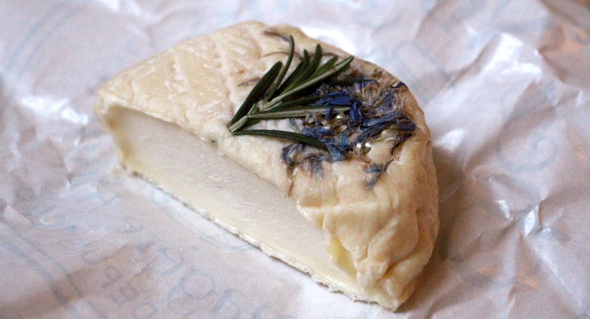 Half a wheel of Berrichon cheese with dried herbs on top