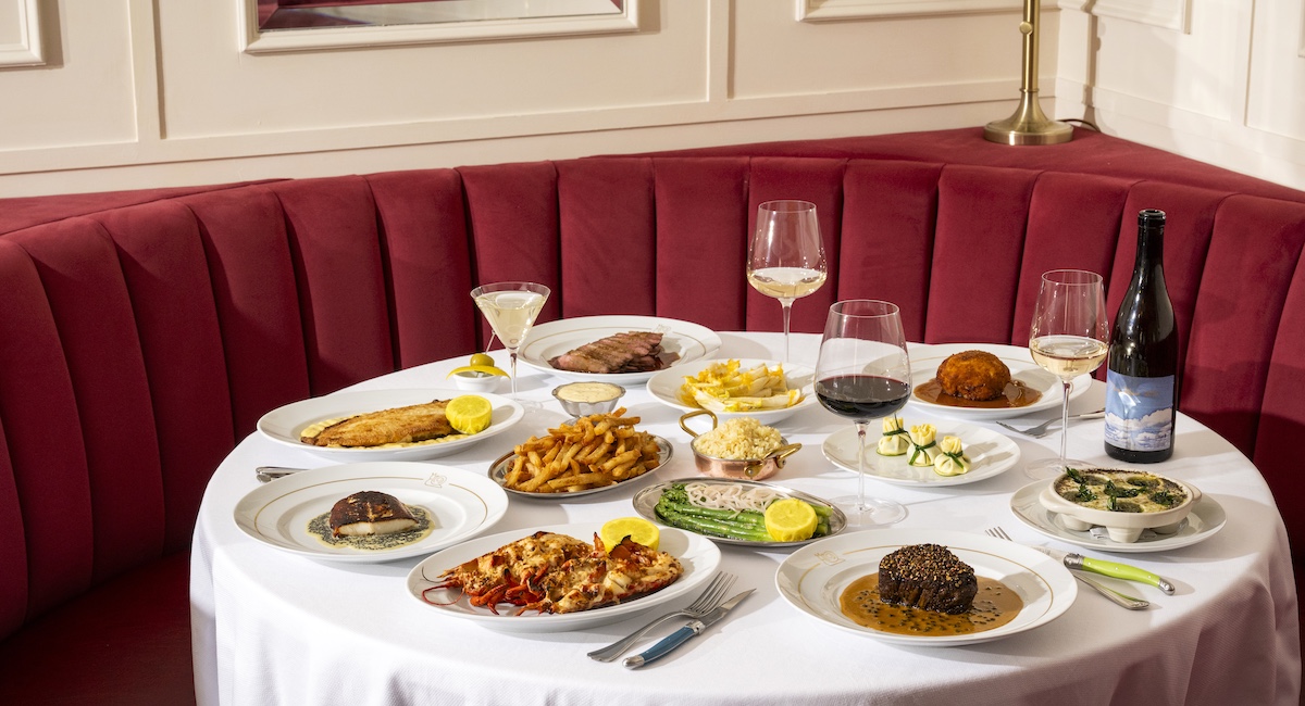 Various French dishes laid out on table in front of red booth