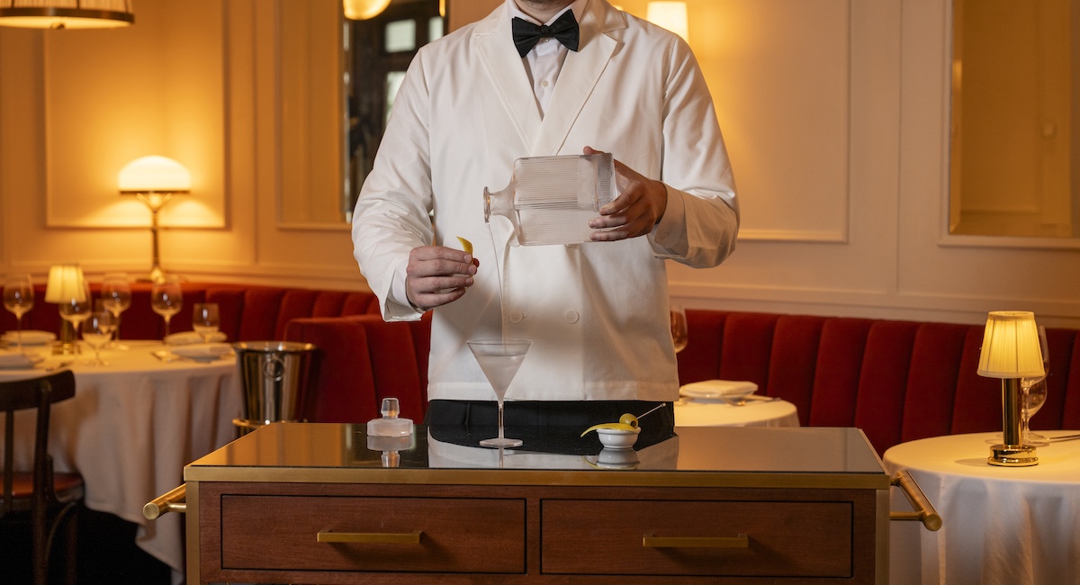Man in white jacket serving ice cold martini from decanter