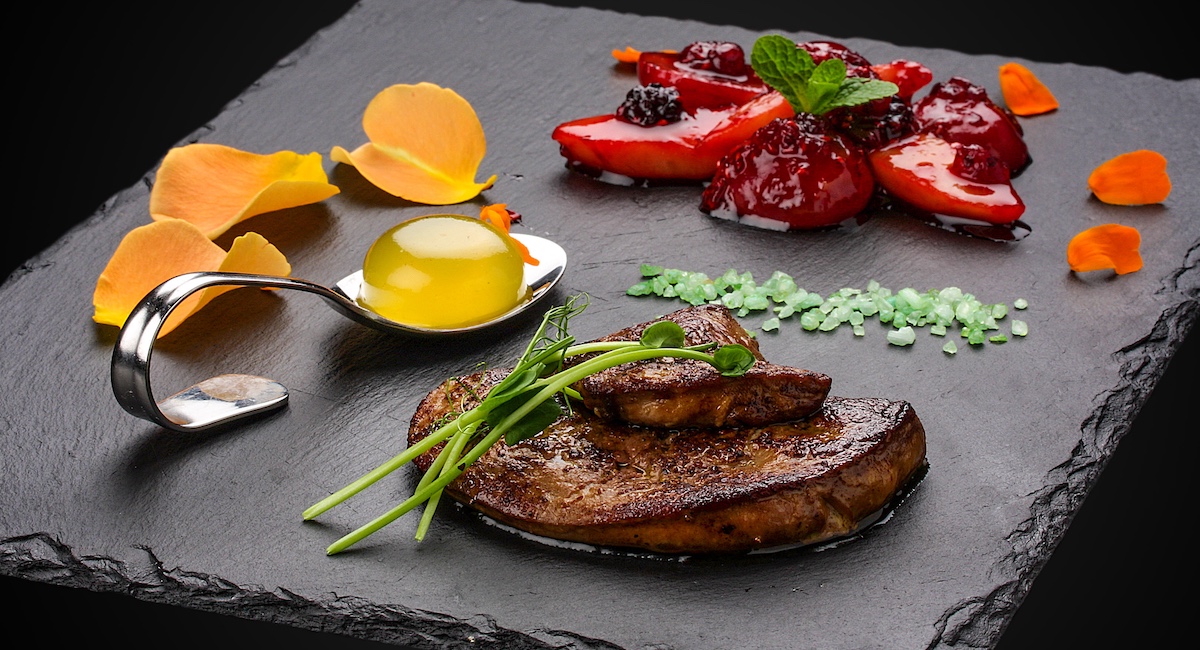 Foie Gras with berries flambe on a dark background